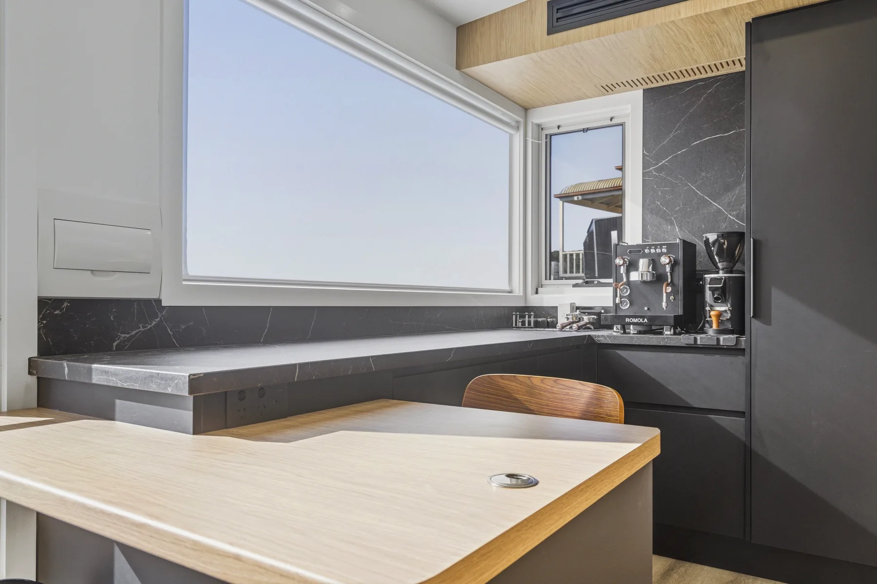 Modern dark kitchen display with stone benchtop and coffee station in the Kitchen Wizard showroom